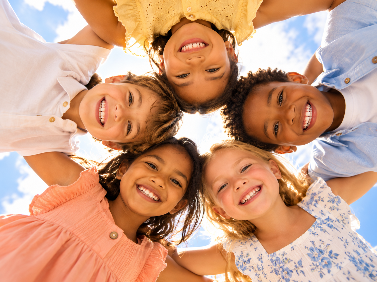 Five smiling children gathered in a circle beneath a bright sky
